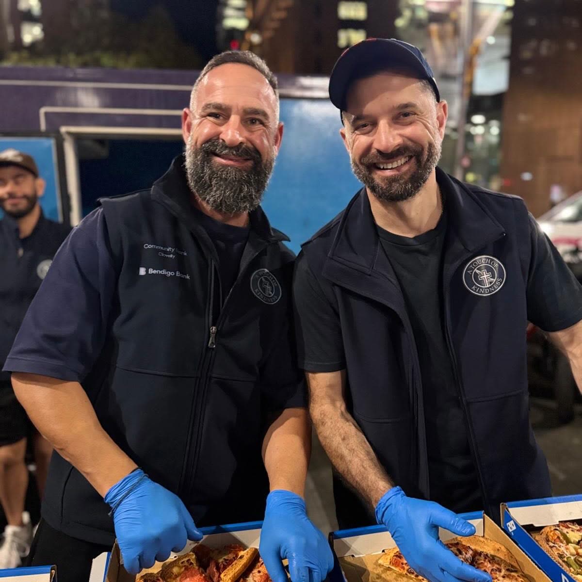Two volunteers in gloves serving hot food from trays